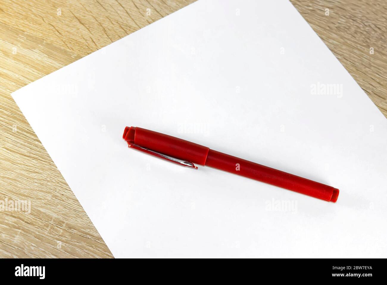 Blank sheet of paper and pen on bright wooden office desk. Ballpoint ...