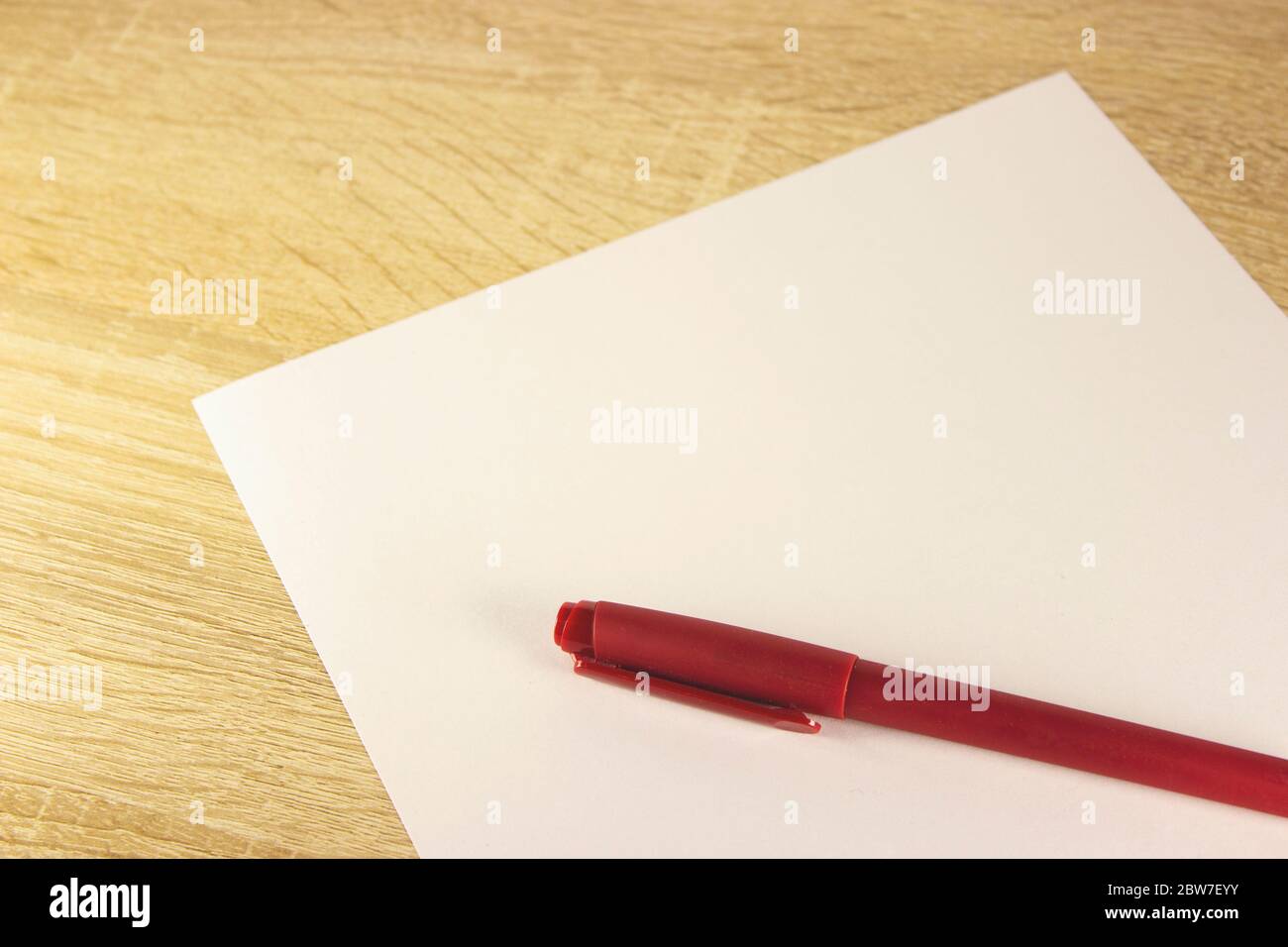 Blank sheet of paper and pen on bright wooden office desk. Ballpoint ...