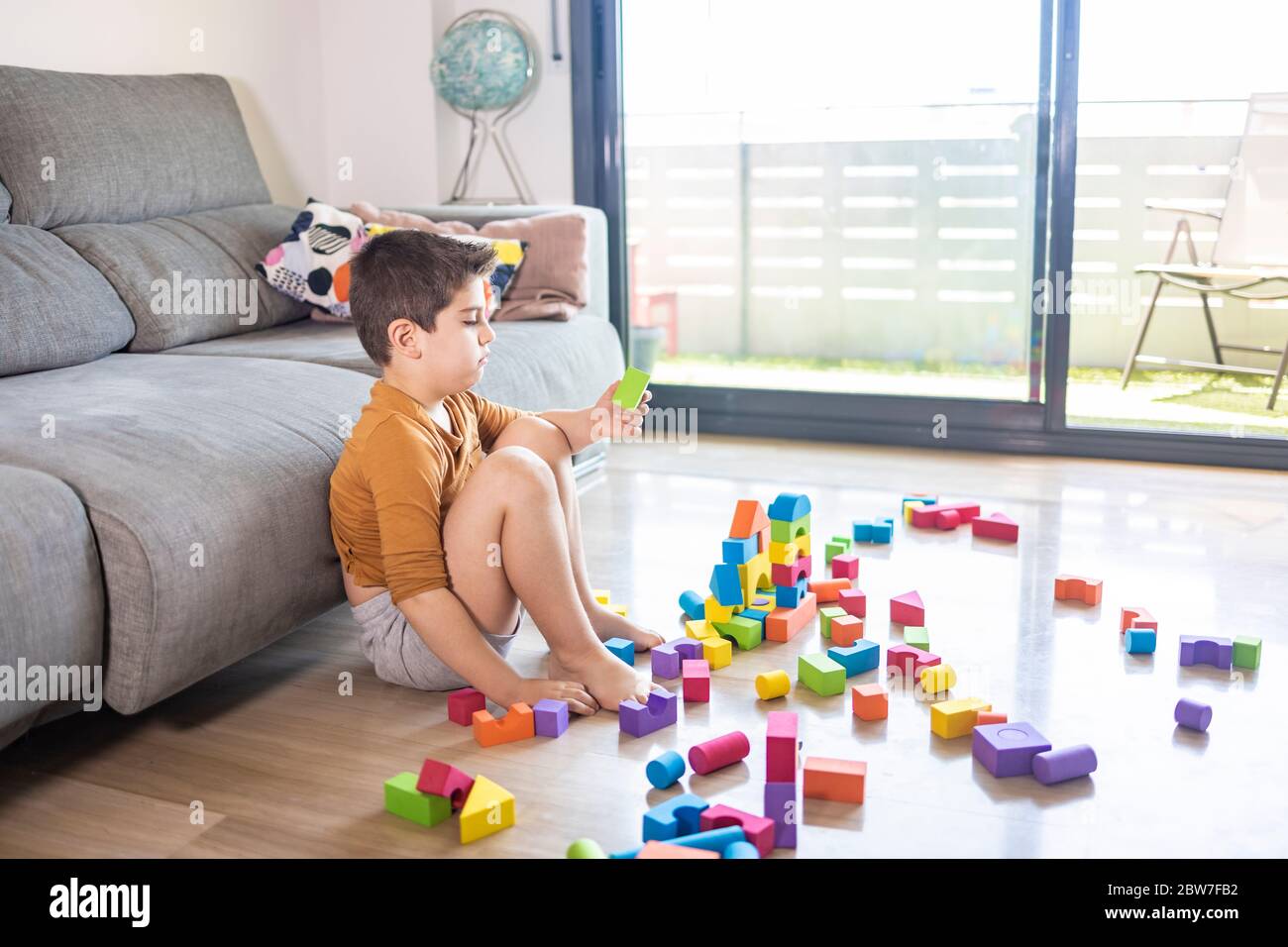 Bored child playing with blocks at home Stock Photo