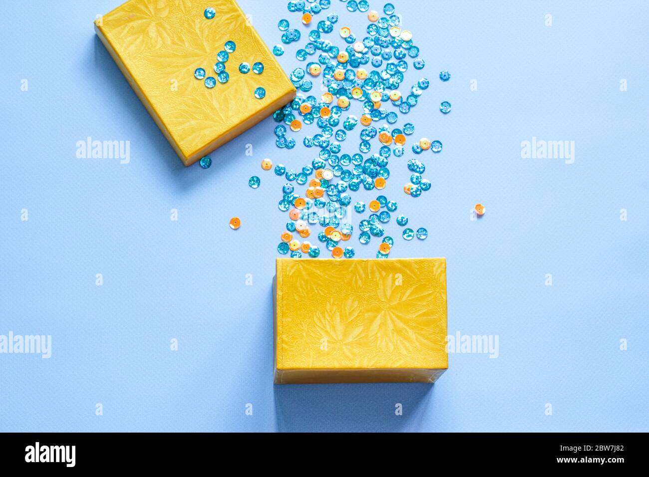 Open gift box with party confetti on a blue background. Flat lay Stock Photo