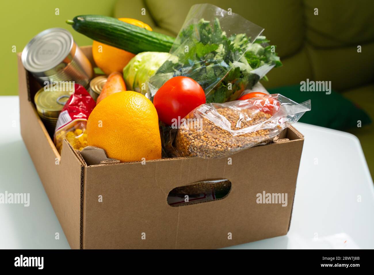 products in a cardboard box are on the kitchen table. food delivery ...