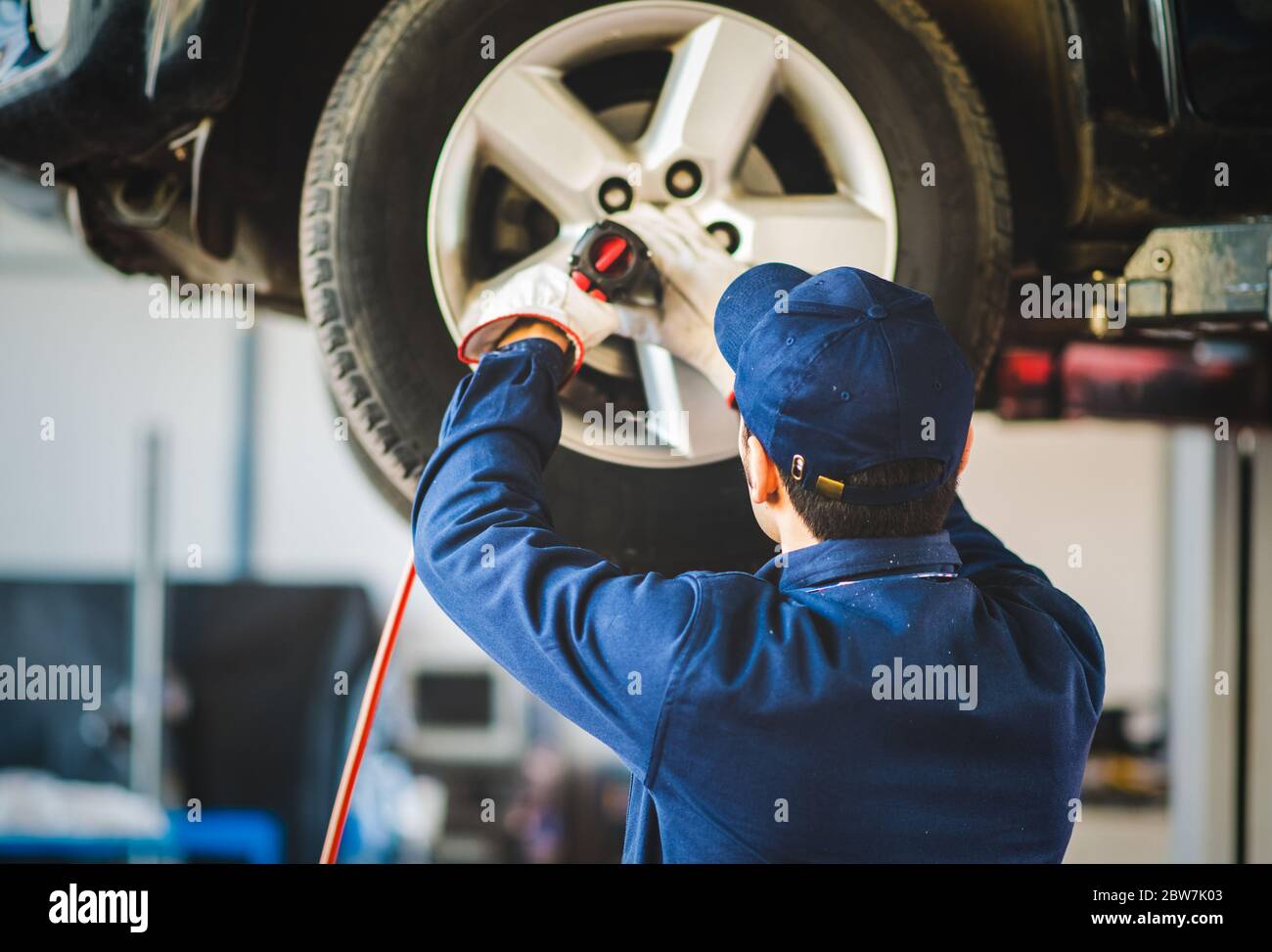 Mechanician changing car wheel in auto repair shop Stock Photo - Alamy