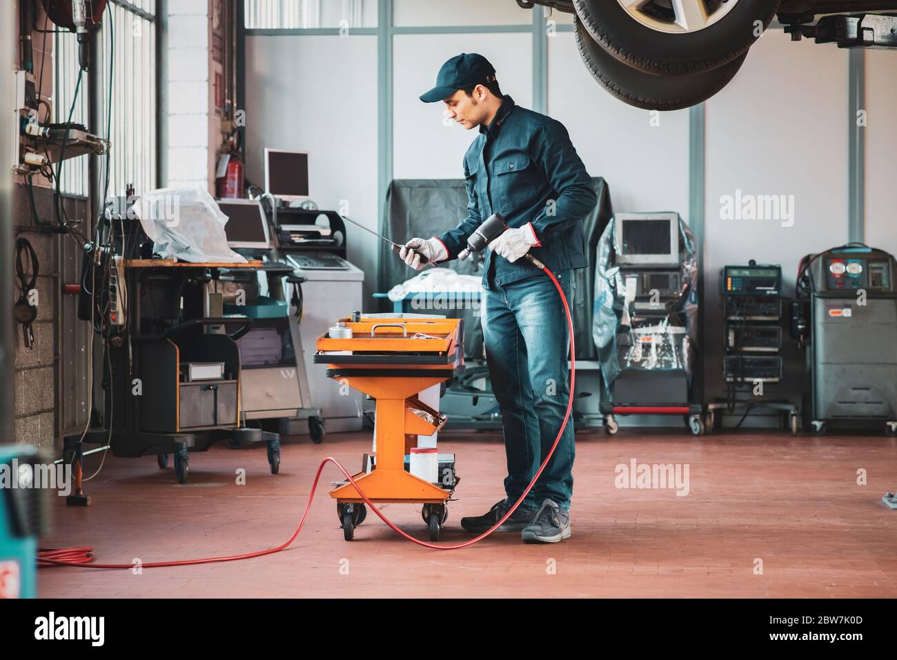 Mechanician changing car wheel in auto repair shop Stock Photo - Alamy