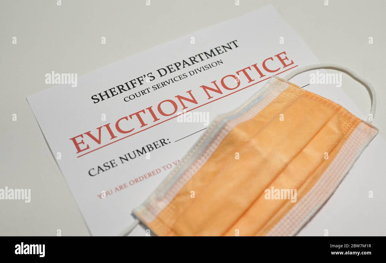 Yellow facial mask laying on top of the sheriff's eviction note for non payment Stock Photo