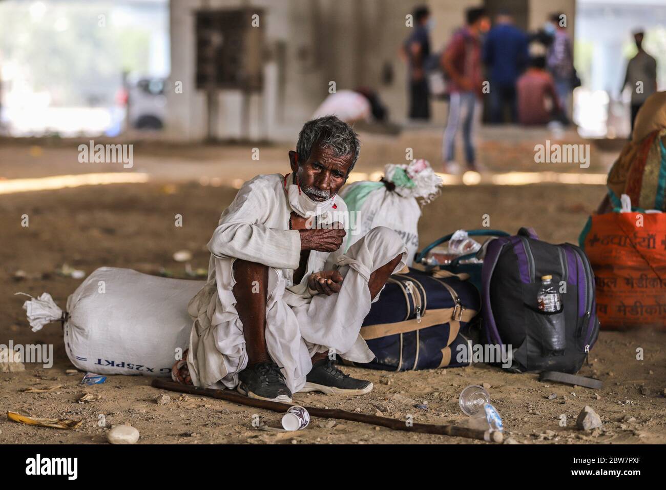 A Migrant worker seen with his luggage under a flyover waiting for transportation. Due to massive job losses after the lockdown put in place to contain the coronavirus pandemic, most migrant workers with their families are returning to their villages. Stock Photo