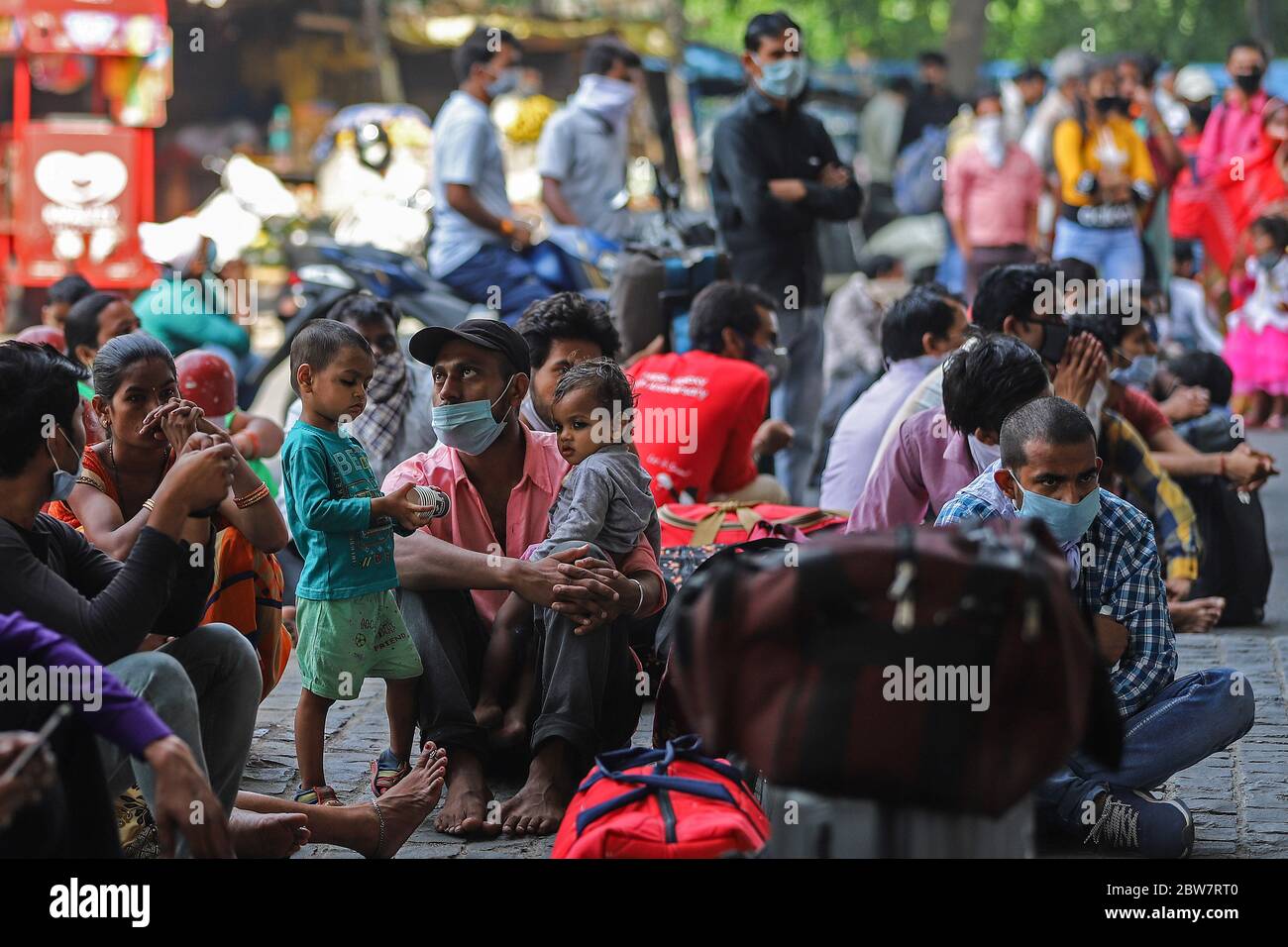 Delhi, India. 18th May, 2020. Migrants wait outside a government school to get screened before boarding buses for the Anand Vihar Railway Station.Due to massive job losses after the lockdown put in place to contain the coronavirus pandemic, most migrant workers with their families are returning to their villages. Credit: Amarjeet Kumar Singh/SOPA Images/ZUMA Wire/Alamy Live News Stock Photo