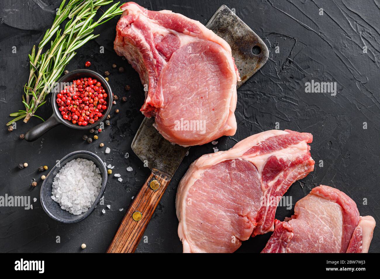Raw pork meat chopes with herbs and spices with meat american cleaver on black background space for text. High quality photo Stock Photo
