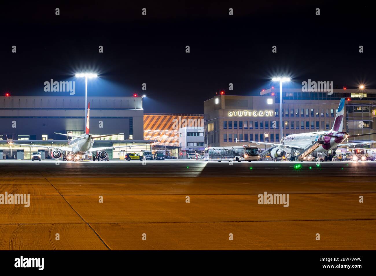 Vorfeld des Flughafen Stuttgart bei Nacht mit Schriftzug 'Stuttgart' im Hintergrund - D-ABZE Eurowings Airbus A320-216 & OE-LWA Austrian Airlines Embr Stock Photo