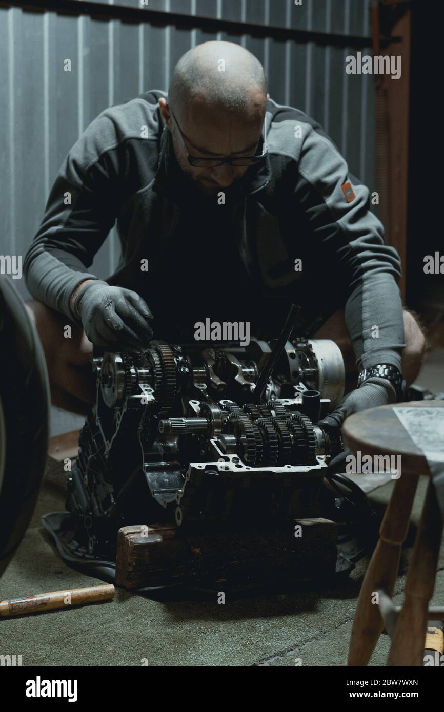 Bike Engine Rrpairing Young man repairing his motorcycle engine in the garage. The motorcycle ...