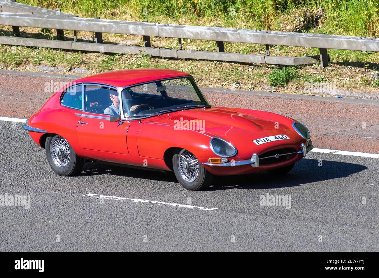 1966 60s red Jaguar 'E' Type British sports car; Vehicular traffic moving vehicles, cars driving vehicle on UK roads, motors, 60s motoring on the M6 motorway highway Stock Photo