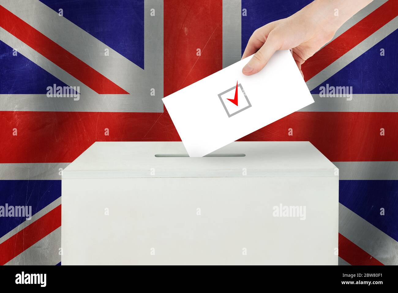 UK Vote concept. Voter hand holding ballot paper for election vote on polling station Stock Photo