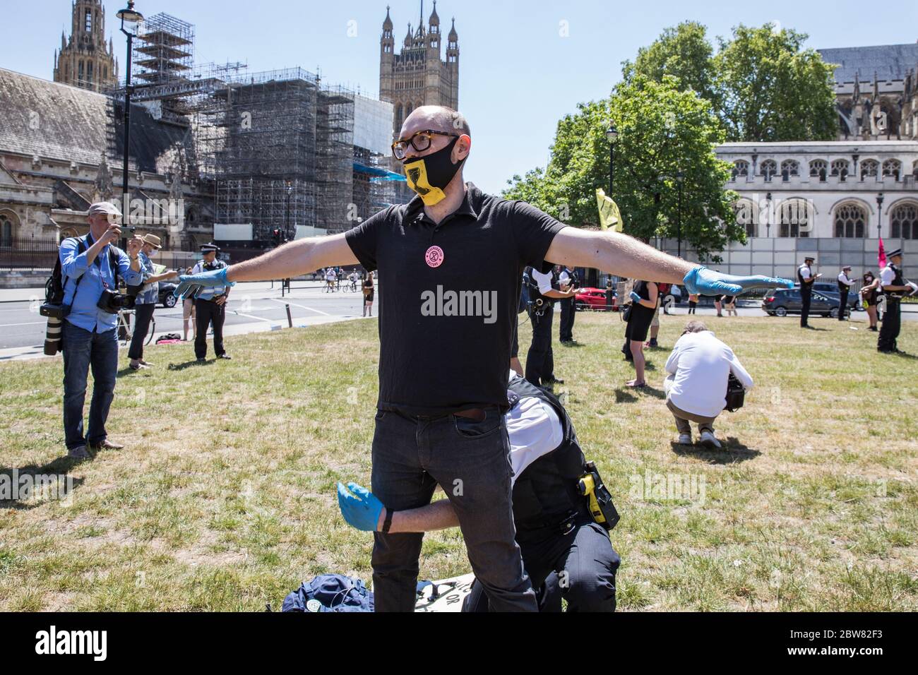Parliament Square, London, UK. 30 May 2020. A few hundred environmental campaigners from Extinction Rebellion demonstrate peacefully in Parliament Square. Protesters hold placards, demand decisive action from the UK Government on the global environmental crisis. Activists are standing and maintain appropriate social distancing. Police questions individual campaigners prompting them to move on; some are body searched and arrests follow for breach of Covid-19 regulations. Stock Photo