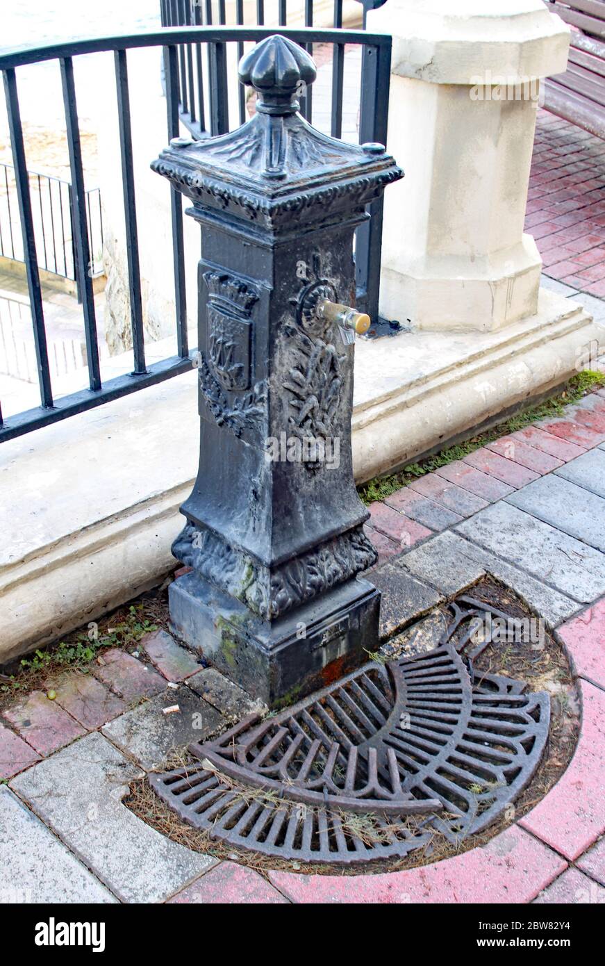 Old an worn water fountain with a broken drainage grate by the esplanade in Sliema, Malta Stock Photo