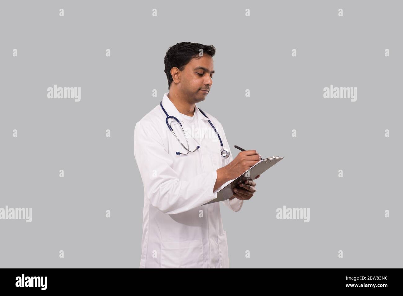 Doctor Writing in clipboard Watching at Clipboard. Indian Man Doctor Clipboard Isolated Stock Photo