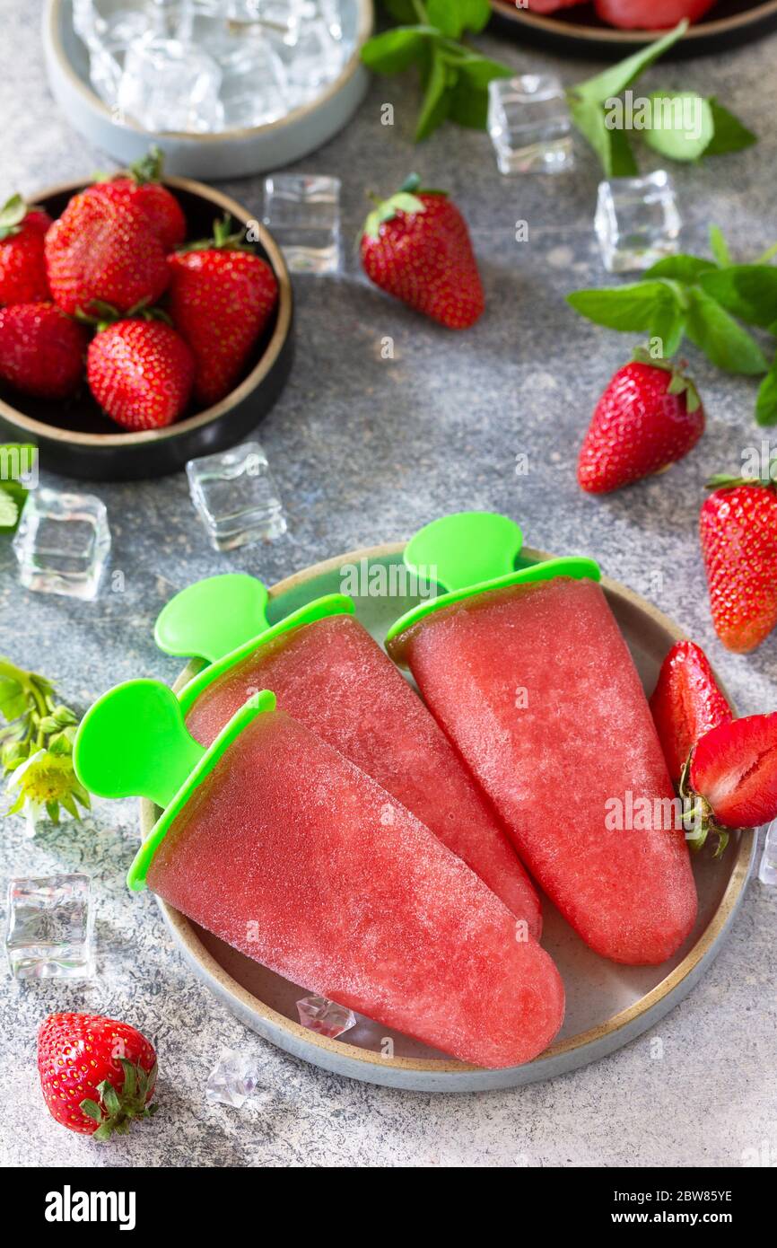 Homemade strawberry frozen fruit juice. Ice cream or popsicles on a light stone or slate table