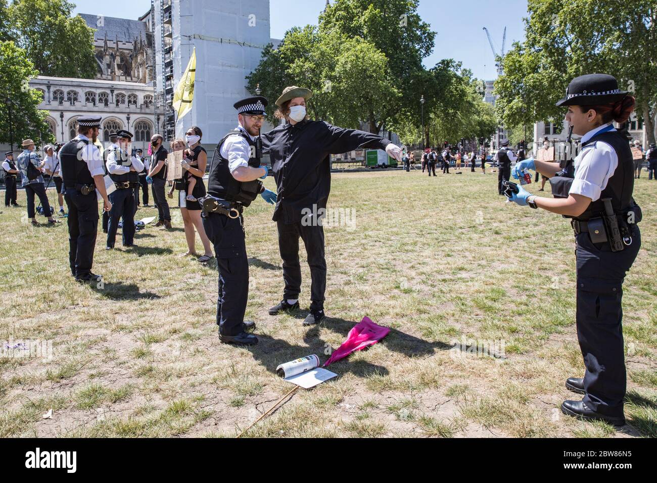 Parliament Square, London, UK. 30 May 2020. A few hundred environmental campaigners from Extinction Rebellion demonstrate peacefully in Parliament Square. Protesters hold placards, demand decisive action from the UK Government on the global environmental crisis. Activists are standing with face masks on and maintain appropriate social distancing. Police questions individual campaigners prompting them to move on; some are body searched and arrests follow for breach of Covid-19 regulations. Stock Photo