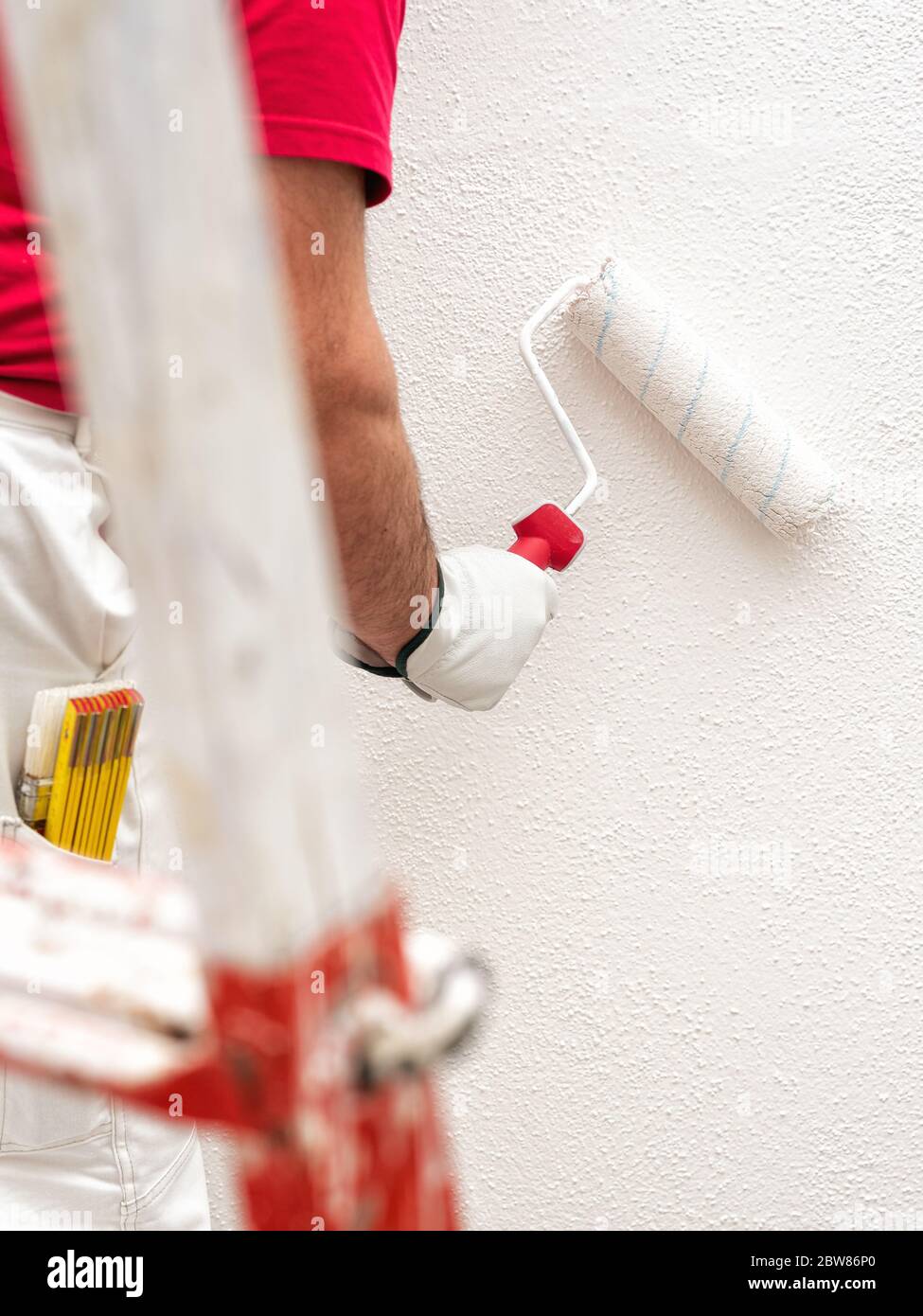 Caucasian house painter worker in white work overalls and with ...