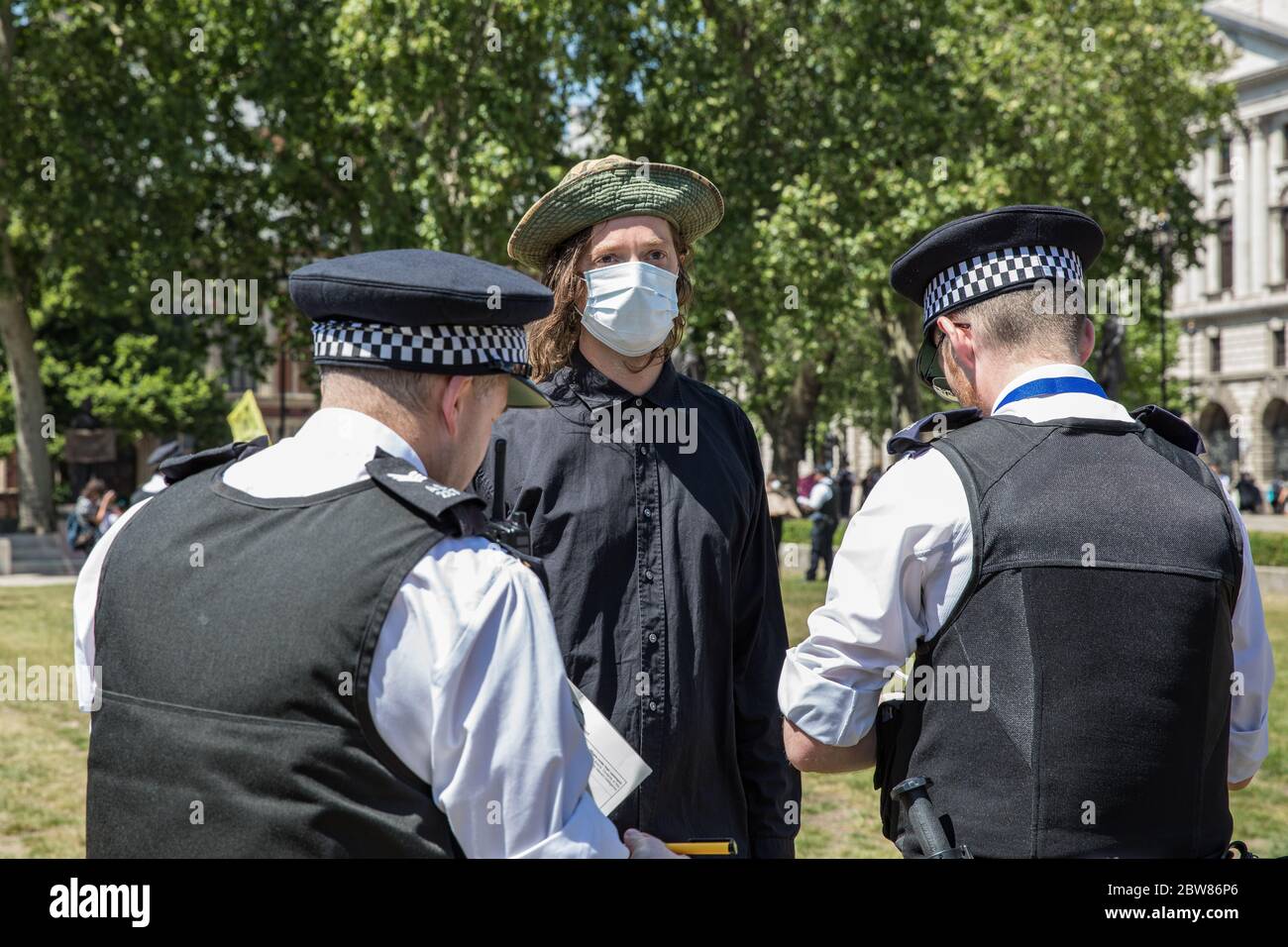 Parliament Square, London, UK. 30 May 2020. A few hundred environmental campaigners from Extinction Rebellion demonstrate peacefully in Parliament Square. Protesters hold placards, demand decisive action from the UK Government on the global environmental crisis. Activists are standing with face masks on and maintain appropriate social distancing. Police questions individual campaigners prompting them to move on; some are body searched and arrests follow for breach of Covid-19 regulations. Stock Photo