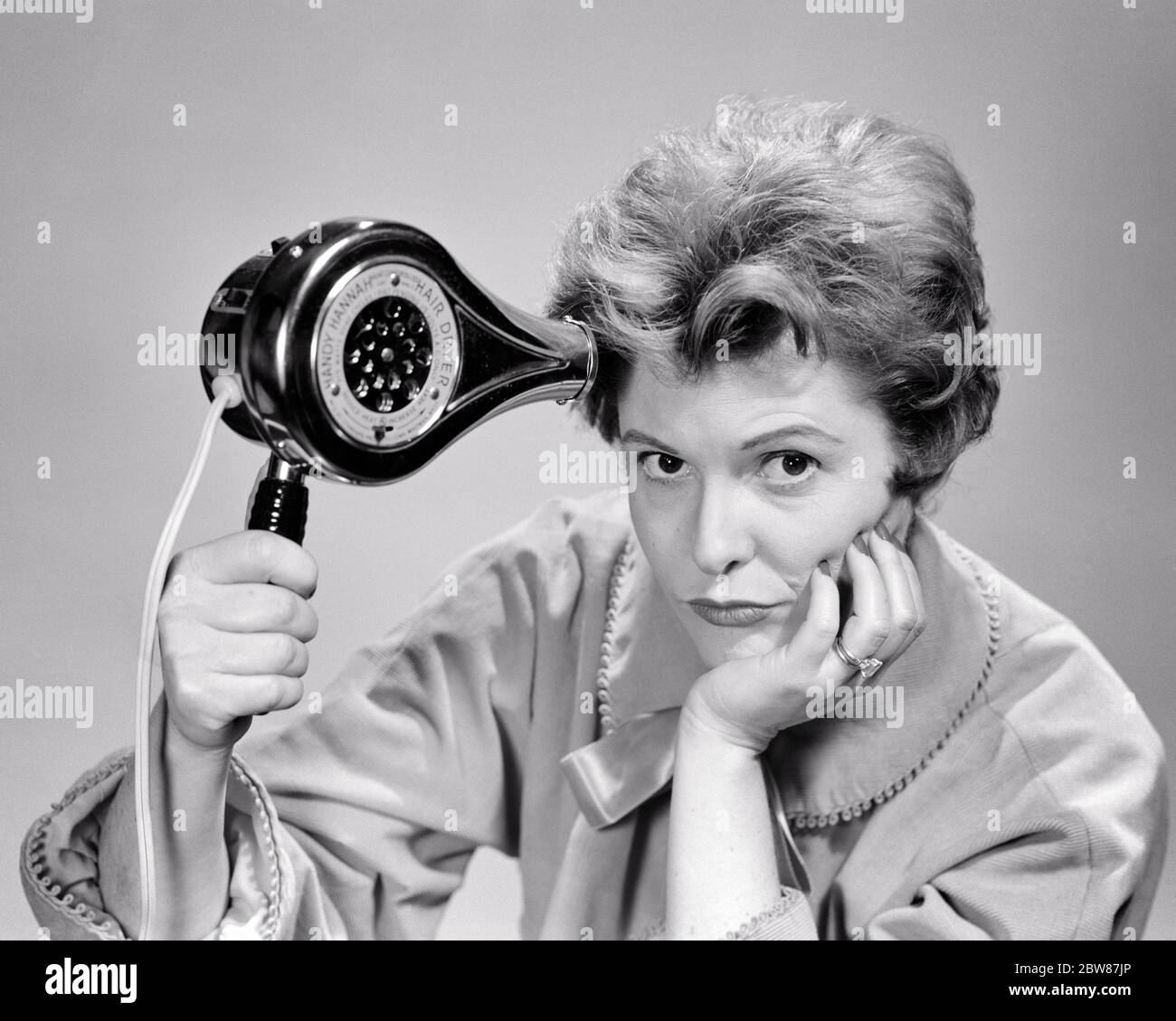 1950s WOMAN BAD HAIR DAY HOLDING AN ELECTRIC HAIR DRYER LOOKING AT CAMERA  WITH AN UNHAPPY DISSATISFIED FACIAL EXPRESSION - c605 DEB001 HARS WORRY  LIFESTYLE ANNOYED FEMALES STUDIO SHOT MOODY HOME LIFE