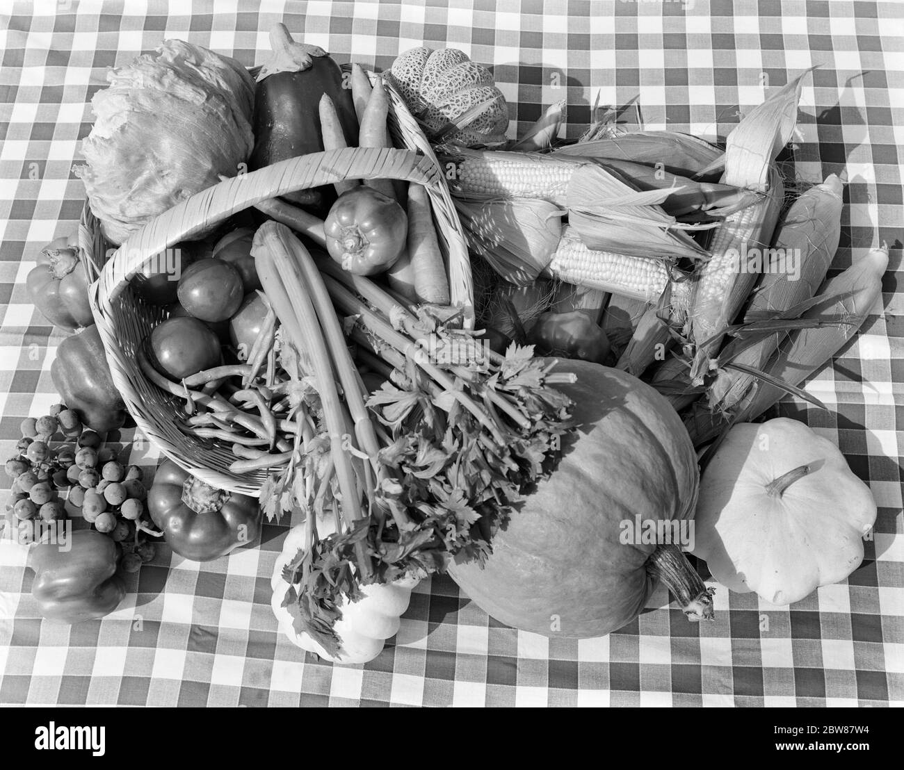 1950s OVERHEAD OF ASSORTMENT OF FRUITS & VEGETABLES WITH BASKET ON CHECKERED TABLECLOTH - f10374 HEL001 HARS OLD FASHIONED Stock Photo