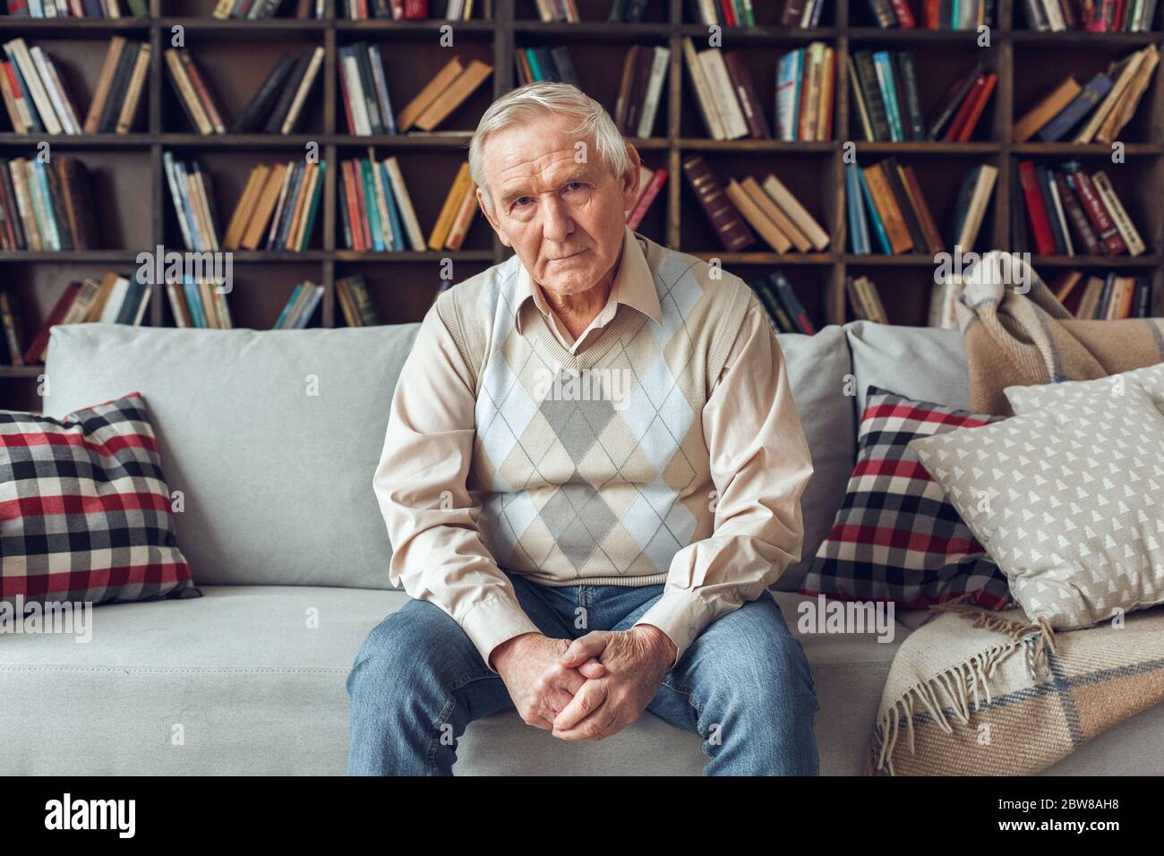 Senior man alone sitting at library looking camera confident Stock Photo
