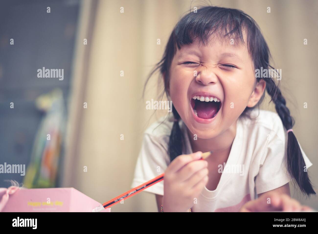 Asian girl doing homework her screaming crazy and mad shouting and yelling with aggressive expression in home the feeling of being upset because of Stock Photo