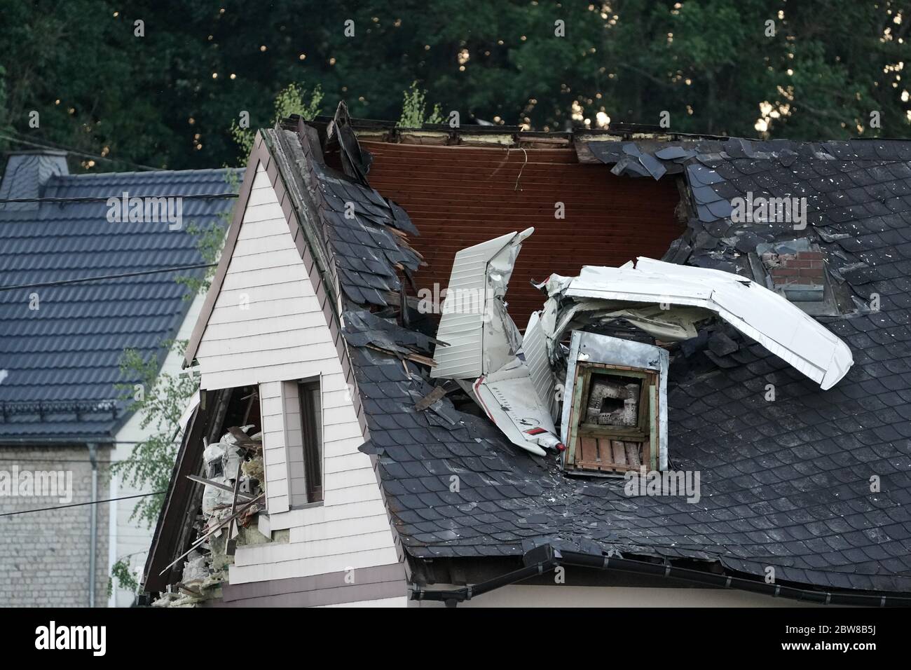 Langenhahn, Germany. 30th May, 2020. Parts of the wreckage of a small airplane protrude from the roof of a residential building. A small plane crashed into the roof of a house in Langenhahn in the Westerwald district on Saturday. The pilot was injured and was taken to hospital, a police spokesperson said. Credit: Thomas Frey/dpa/Alamy Live News Stock Photo