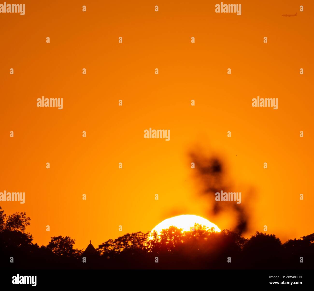 Wimbledon, London, UK. 30 May 2020. Spectacular orange sunset behind Wimbledon Hill on day 68 of Coronavirus lockdown with a departing aircraft from Heathrow. Credit: Malcolm Park/Alamy Live News. Stock Photo