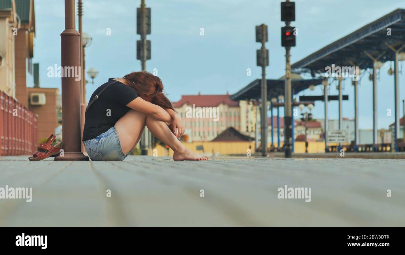 Sad girl sitting on the tiles of the railway station and crying Stock ...