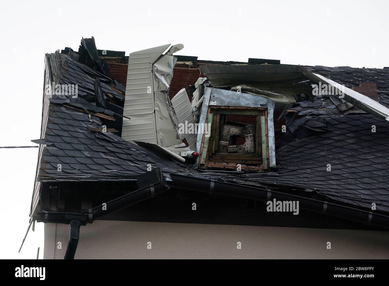 Langenhahn, Germany. 30th May, 2020. Parts of the wreckage of a small airplane protrude from the roof of a residential building. A small plane crashed into the roof of a house in Langenhahn in the Westerwald district on Saturday. The pilot was injured and was taken to hospital, a police spokesperson said. Credit: Thomas Frey/dpa/Alamy Live News Stock Photo