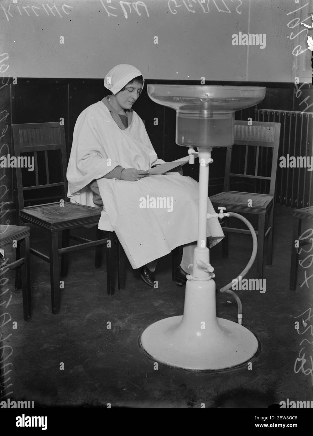 White robed figures at Englands first inhalatorium . Fumes that kill the flu germ . A lady patient leading in the Inhalation Chamber . 15 January 1929 Stock Photo