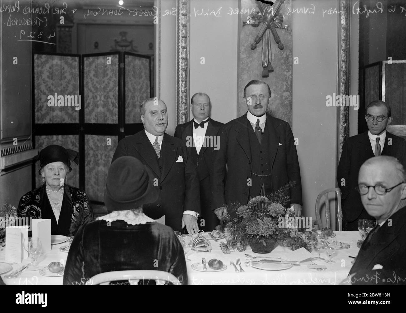 Honouring a money maker . Director of the French mint entertained in London  . At the Anglo French Luncheon Club gathering , Hotel Victoria . Left to  right : Lady Evans ,