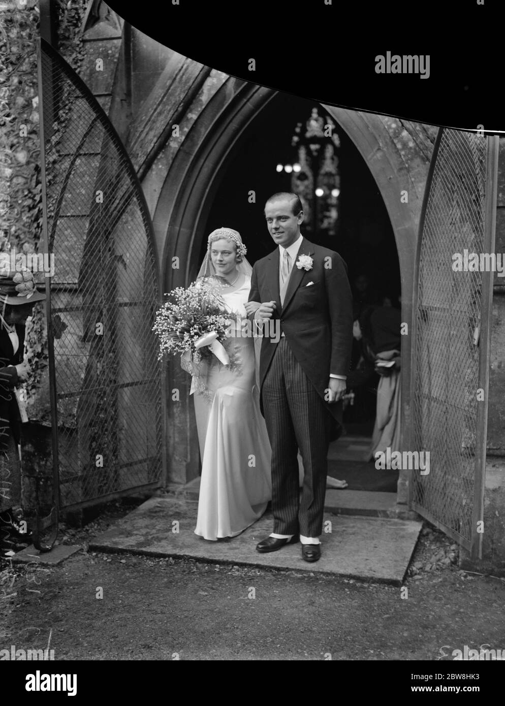 Historic pearls and bridal flowers worn by bride at Oxen society wedding . Miss Patricia Smiley was married at Whitchurch , Oxon to Mr Rupert Tollemache . The bride and bridegroom leaving after the ceremony . 22 October 1931 Stock Photo