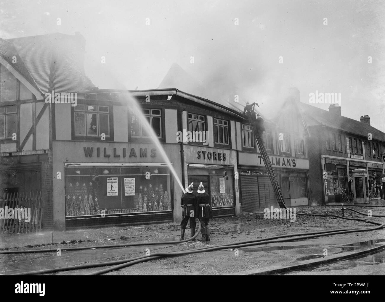 Firemen attempt to put out fires in a parade of shops in Welling , Kent . 1937 . Stock Photo