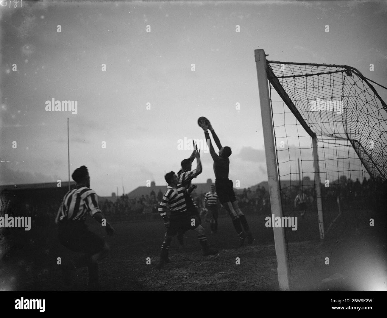 A goalkeeper catches the ball while under pressure from the attackers . 1935 Stock Photo