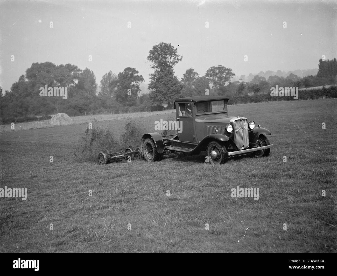 Mowing the grass . The mower is attached to the back of a truck . 1937 Stock Photo