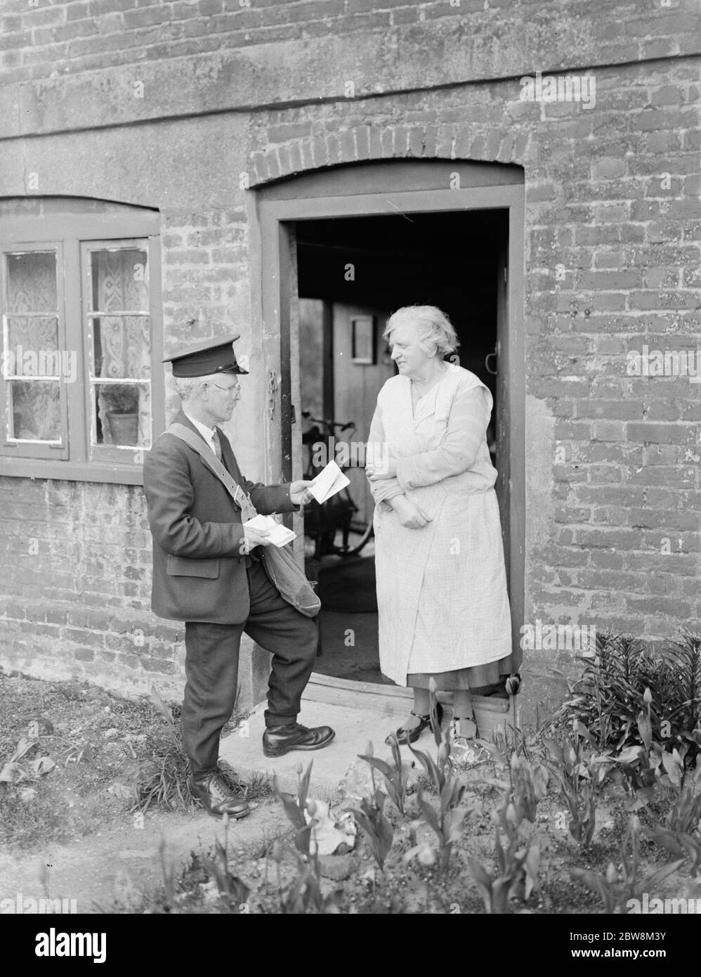 Postman delivering letters to the front door . 1935 Stock Photo