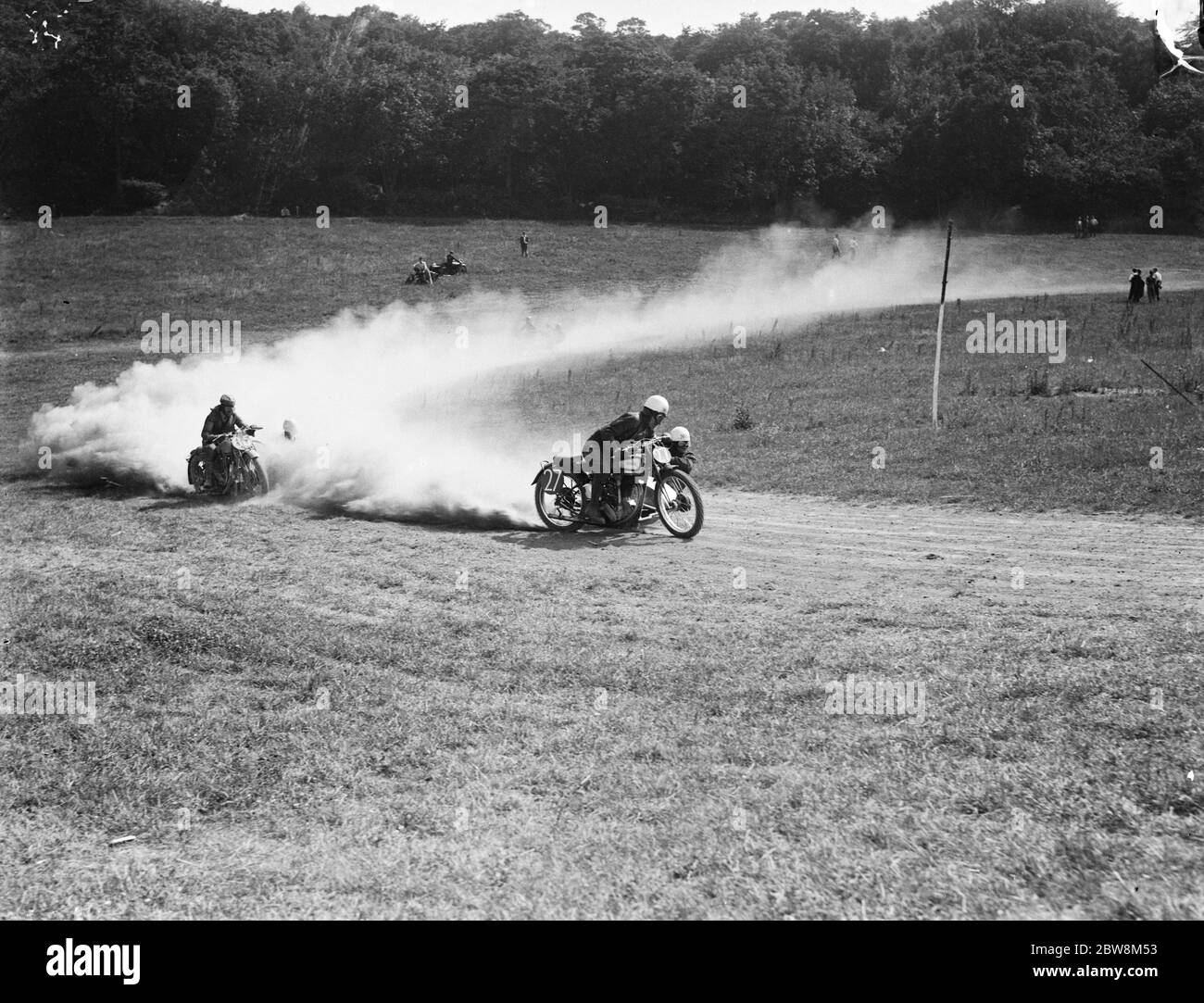 Motorcycle sidecar racing in the dust with his team mate leaning of the side to keep the bike balanced . 1935 Stock Photo