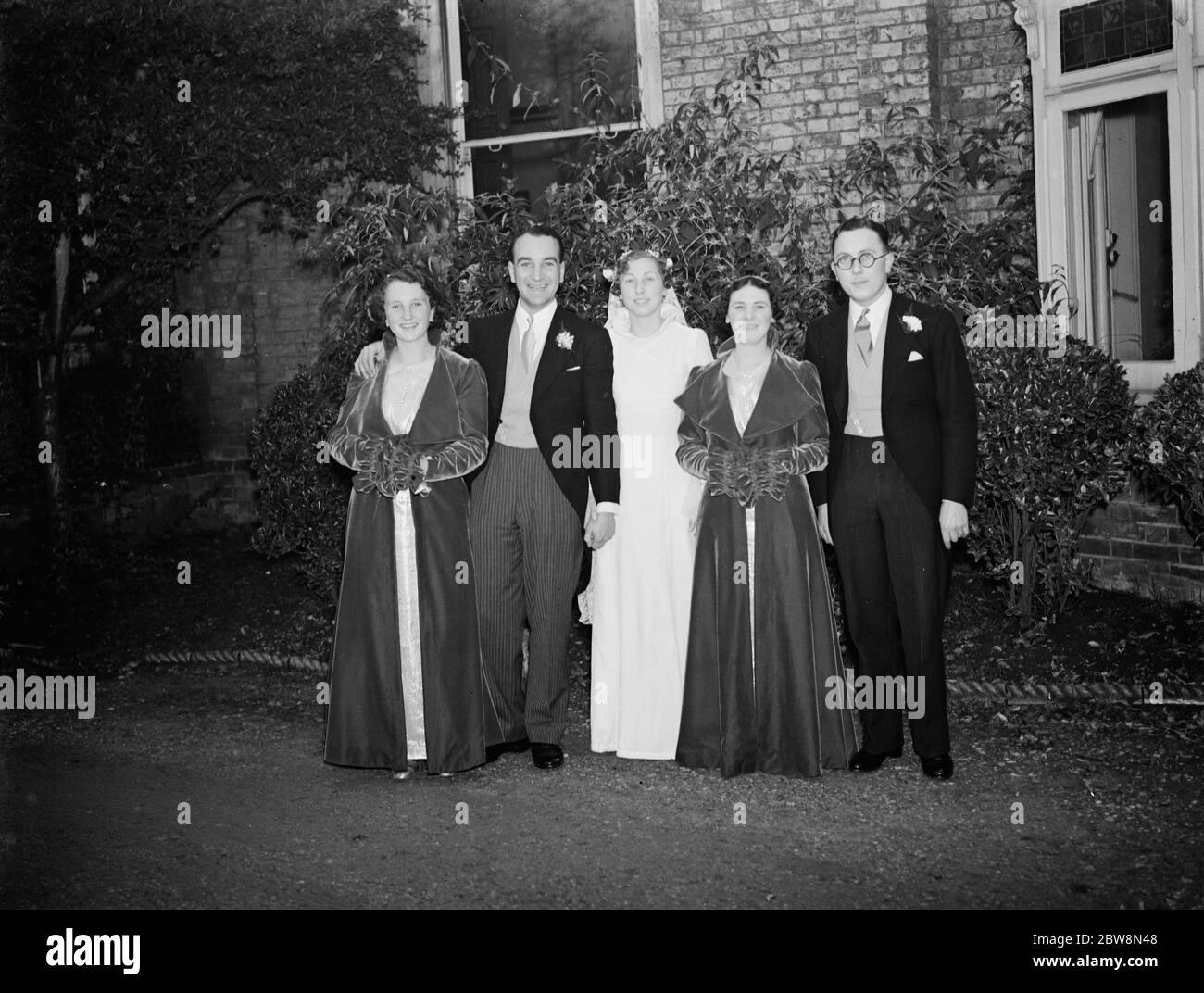 The wedding of J Houlgate and D Wonersley . The bride and bridegroom with the bridesmaids and the best man . 1937. Stock Photo