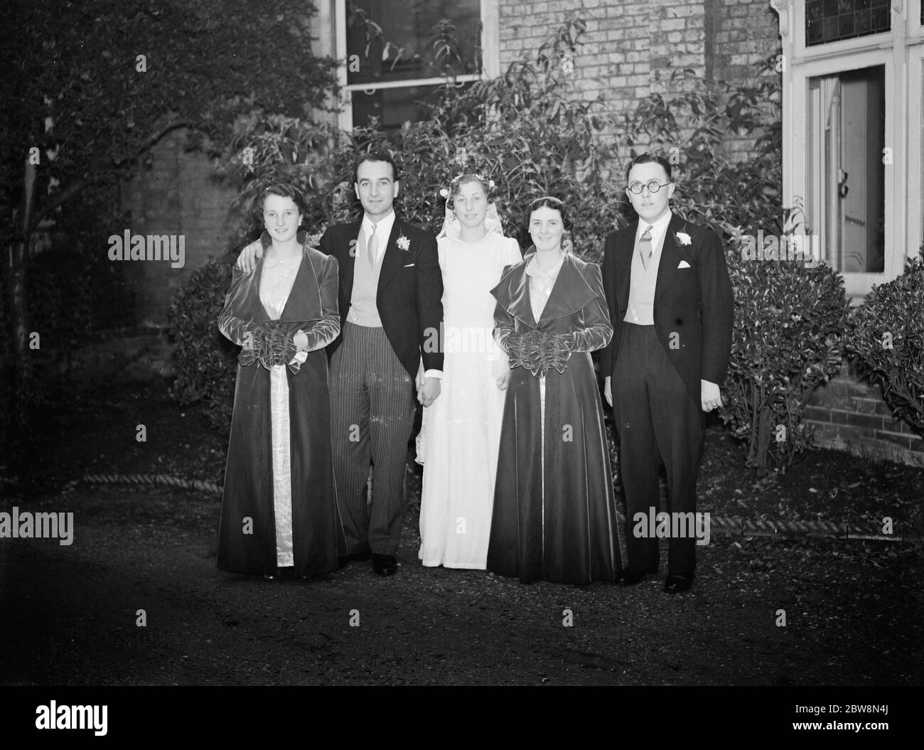 The wedding of J Houlgate and D Wonersley . The bride and bridegroom with the bridesmaids and the best man . 1937. Stock Photo