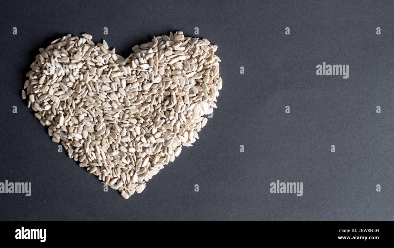 Top view of sunflower seeds in a heart shape on black background