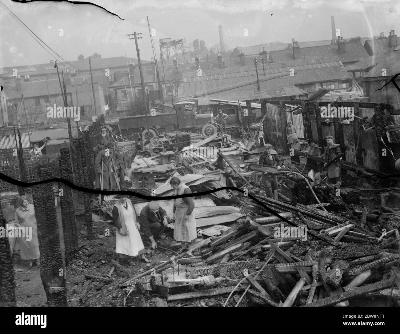 Locals look over the remains of the Dartford timber yard fire . 1936 Stock Photo