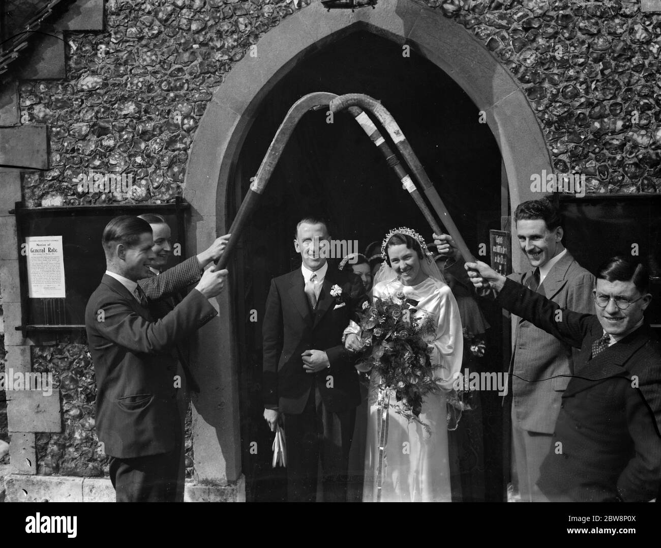 The wedding of Bretnall and Burton in Crayford walk out through a guard of hockey sticks . 1936 Stock Photo