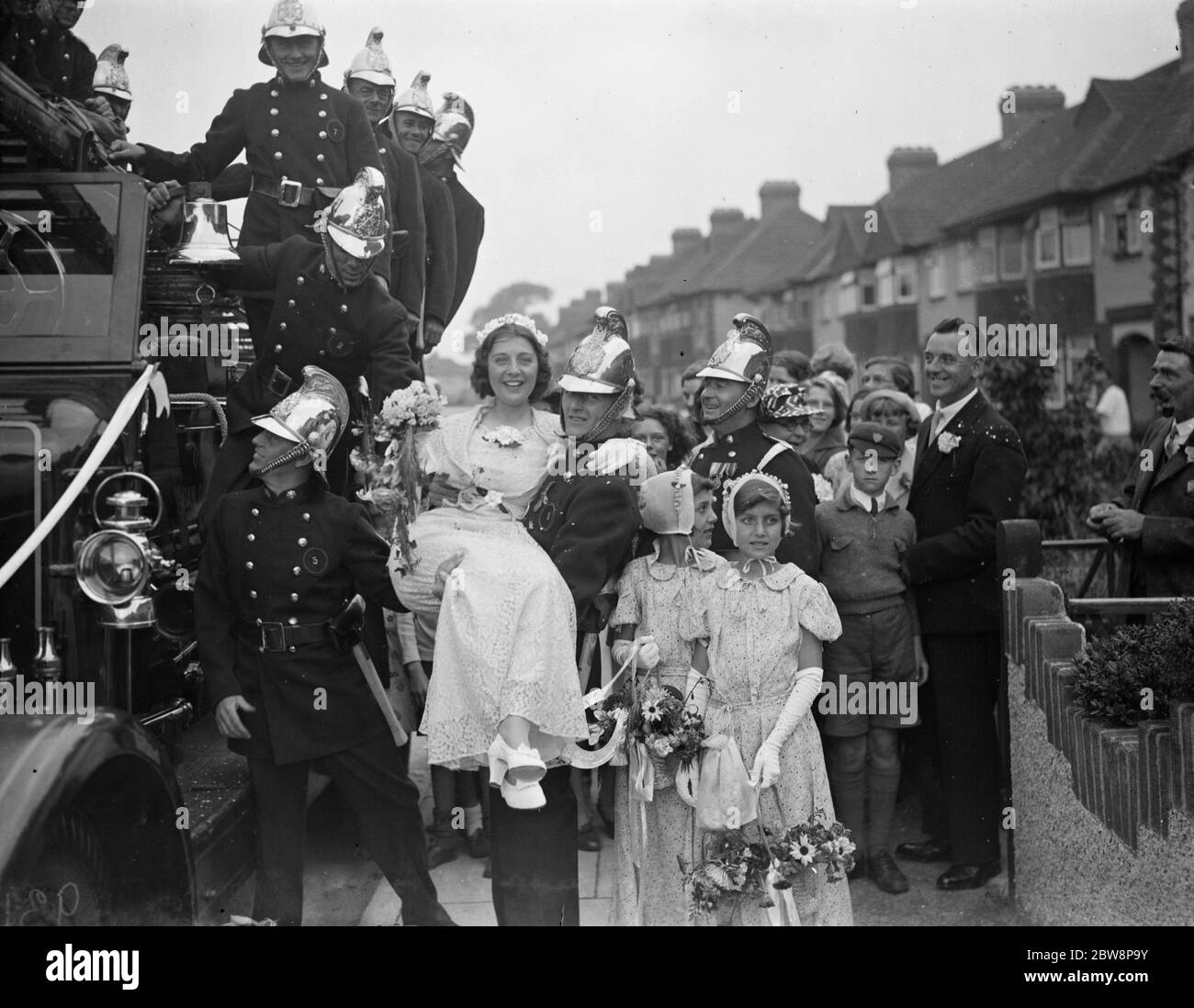 The wedding of firemen A Schofield and Miss E Gifford . The bride is being carried to their wedding vehicle . 1938 Stock Photo