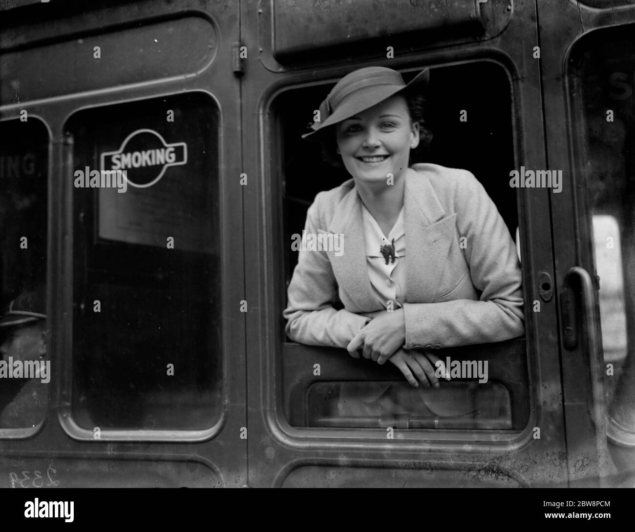 A smiling young woman looking out of a train carriage window . 1935 Stock Photo