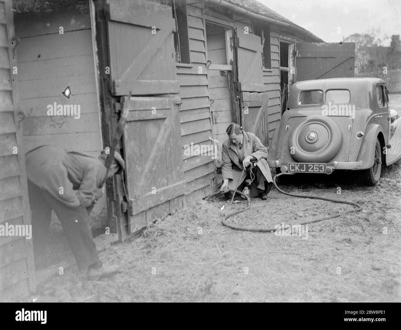 Men gassing rats with exhaust fumes from a car in the farmyard . 1935 Stock Photo
