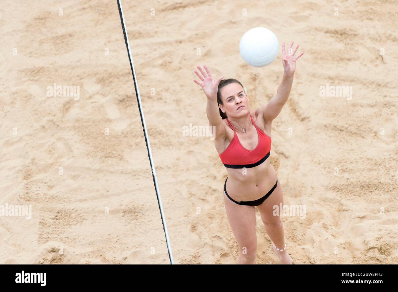 Young woman with white ball playing volleyball on beach. Summer vacation and sport concept Stock Photo