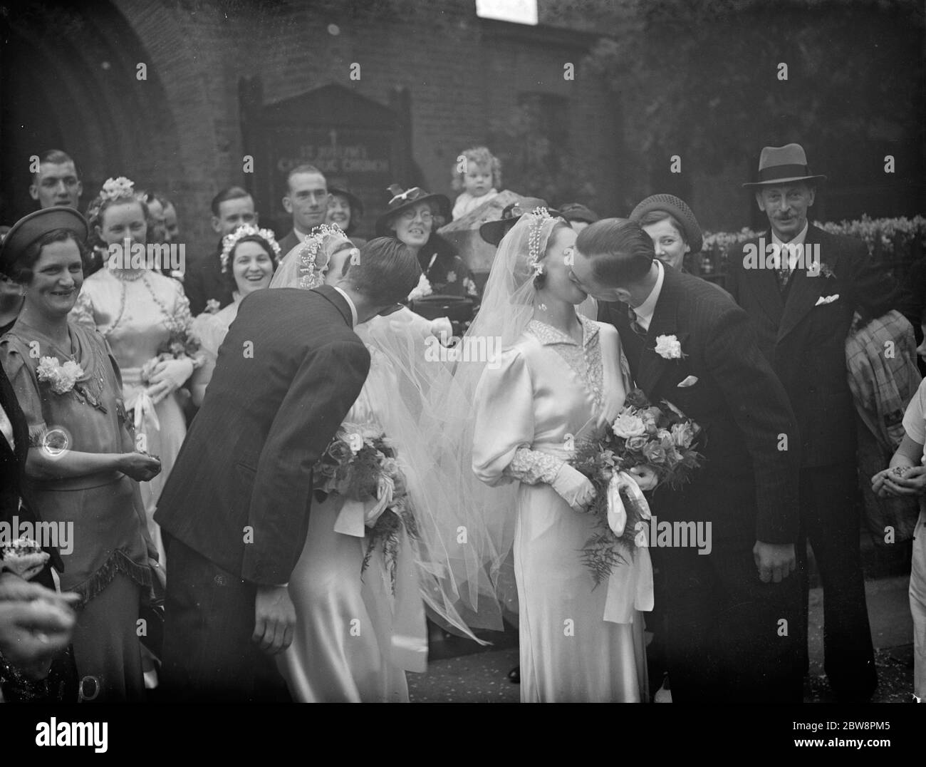The double wedding of the O ' Brian sisters . The marriages of Mr W T Johnson and Miss A O ' Brian and Mr R H Clark and Miss E O ' Brian . The bridegrooms kiss their brides . July 1938 Stock Photo