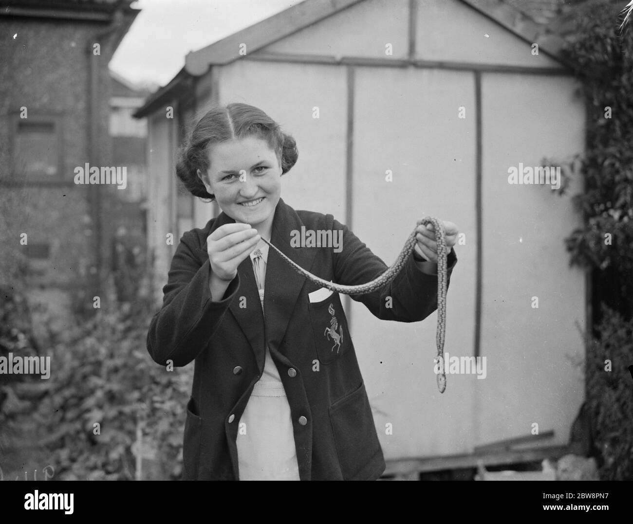 A women holds aloft a dead snake found under a garage in Sidcup . 1938 Stock Photo