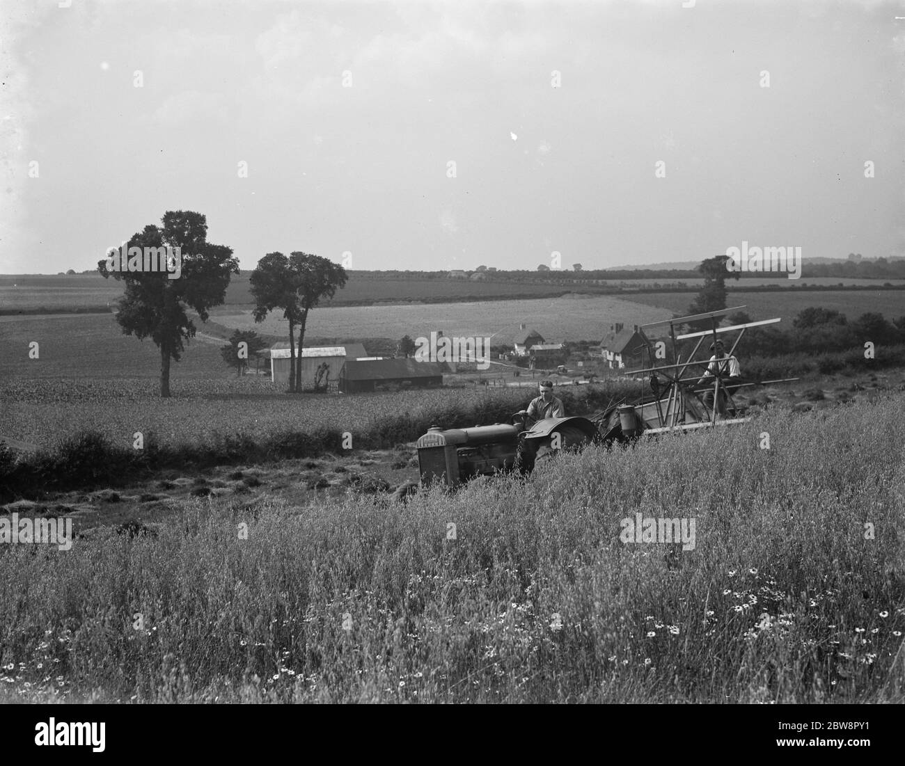 A farmer collects his harvest with his combine in Dene Bottom . March 1938 . Stock Photo